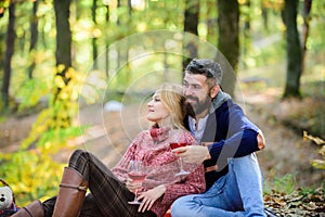 Couple cuddling drinking wine. Happy loving couple relaxing in park together. Romantic picnic with wine in forest