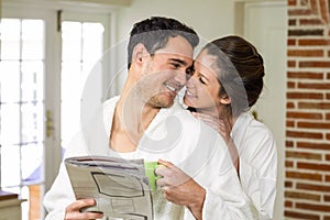 Couple cuddling while having tea and reading newspaper