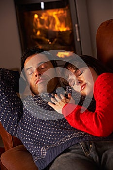 Couple Cuddling On Sofa By Cosy Log Fire