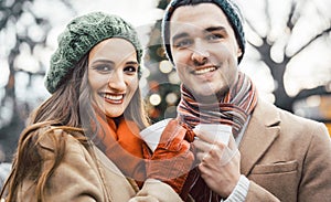 Couple with cups of mulled wine on Christmas market