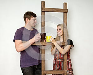 A couple with cups is resting during the repair near a wooden co