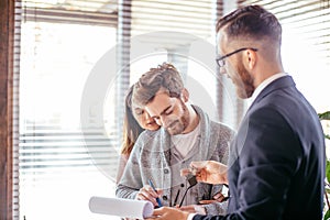 Couple customers signing papers with mortgage broker making purchase deal