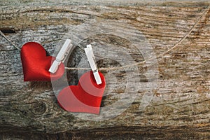 Couple of cute red hearts on string with pegs on wooden background. Romantic Valentine`s Day scene with copy space.