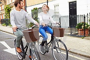 Couple Cycling Along Urban Street Together