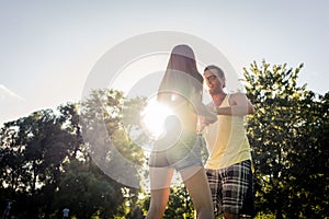 Couple dancing bachata in park backlit training dip figure