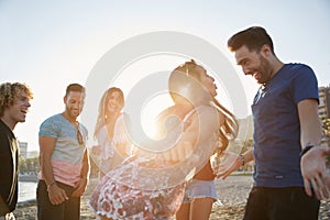 Couple dancing on beach partying with friends