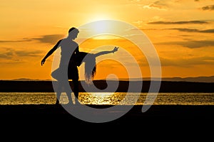 A couple dancing by the sea at sunset