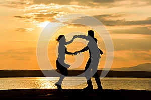 A couple dancing by the sea at sunset