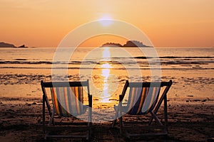 Couple of deck chairs at dusk on sea beach. Relax.