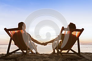 Couple in deckchairs on the beach enjoying beautiful sunset