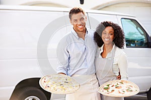 Couple Delivering Pizza Standing In Front Of Van