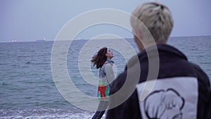 Couple in denim jackets walk by the sea