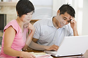 Couple in dining room with laptop looking unhappy