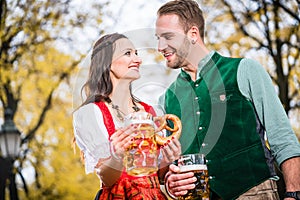 Couple in Dirndl and Tracht having Pretzel and Bier