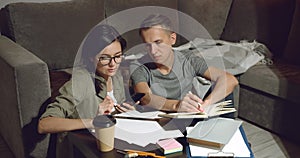 Couple discussing design of a new apartment or working together sitting on the floor and using a smartphone at home