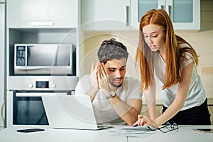 Couple discussing about domestic bills at home while looking at documents