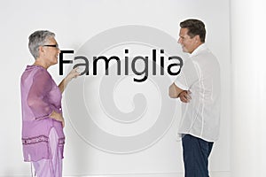 Couple discussing family issues against white wall with Italian text Famiglia photo