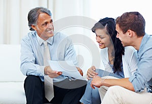 Couple discussing with financial planner. Mature advisor showing financial plan to young couple at home.