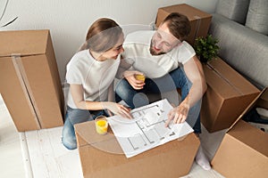 Couple discussing house plan sitting on floor with moving boxes