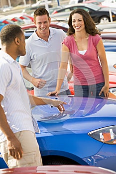 Couple discussing new car with salesman