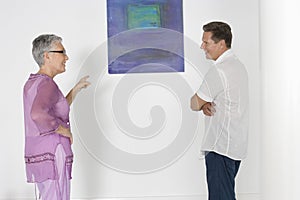 Couple Discussing Over Painting In Art Gallery