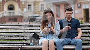 Couple in disinterest moment with phones outdoors