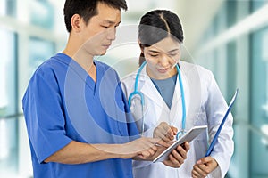 Couple of doctors at work with lab coats, stethoscopy and tablet