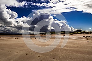 Couple With Dog Taking A Walk On The Sandy Achnahaird Beach In Scotland