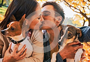 Couple with dogs making selfie while kissing in autumn park