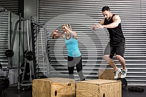 Couple doing box jumps in gym