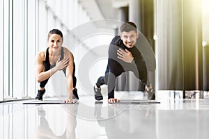 Fitness couple doing plank with one hand at the gym
