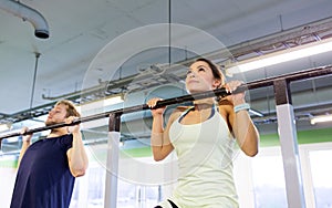 Couple doing pull-ups at horizontal bar in gym