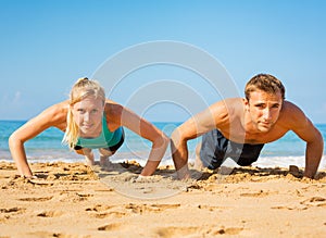 Couple doing push ups on the beac