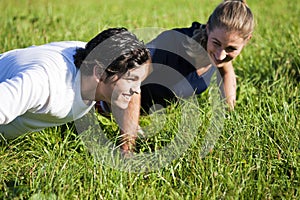 Couple doing push ups in summer grass