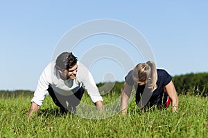 Couple doing push ups in summer grass