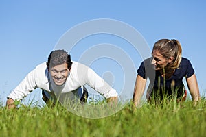 Couple doing push ups in summer grass