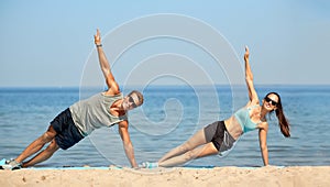 Couple doing side plank exercise on summer beach