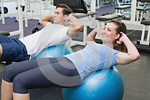 Couple doing sit ups on exercise balls