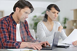 Couple doing their accounts at home using laptop