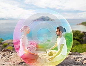 Couple doing yoga in lotus pose with rainbow aura
