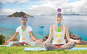 Couple doing yoga in lotus pose with seven chakras