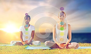 Couple doing yoga in lotus pose with seven chakras