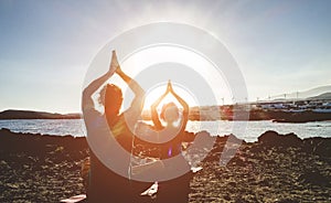 Couple doing yoga outdoor at sunrise in nature - Woman and man meditating together at morning time - Concept of fitness exercise