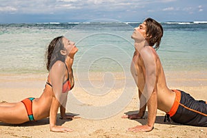 Couple doing yoga and relaxation exercises by the sea