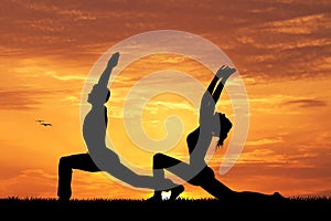 Couple doing yoga at sunset