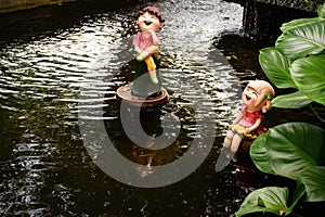 Couple dolls made of clay in pond at small garden.