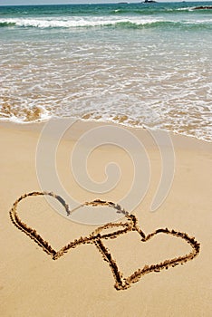 Couple drawing a heart on wet golden beach