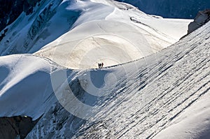 Couple dressed mountaineering clothes with backpacks rising arms with ice axes and enjoying views on the summit top near Aiguille