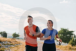 A couple dressed in sportswear runs along a scenic road during an early morning workout, enjoying the fresh air and