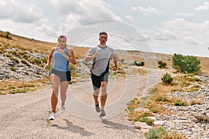 A couple dressed in sportswear runs along a scenic road during an early morning workout, enjoying the fresh air and